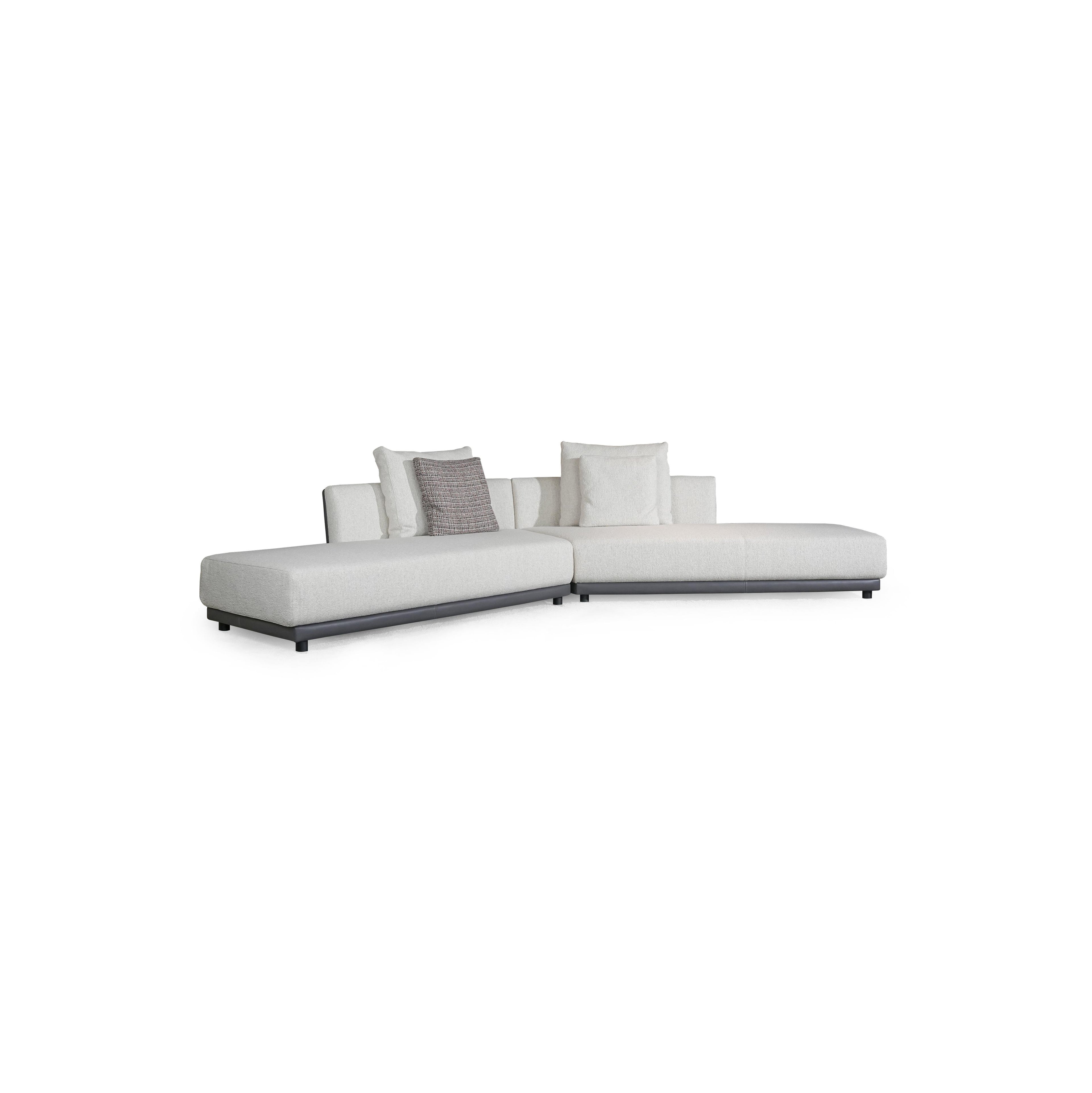 L-shaped sectional sofa with off-white fabric upholstery and dark gray armrests and base. Features multiple cushions, including two textured throw pillows. Supported by short, dark legs. Designed for seating and lounging. Category: furniture/sofas