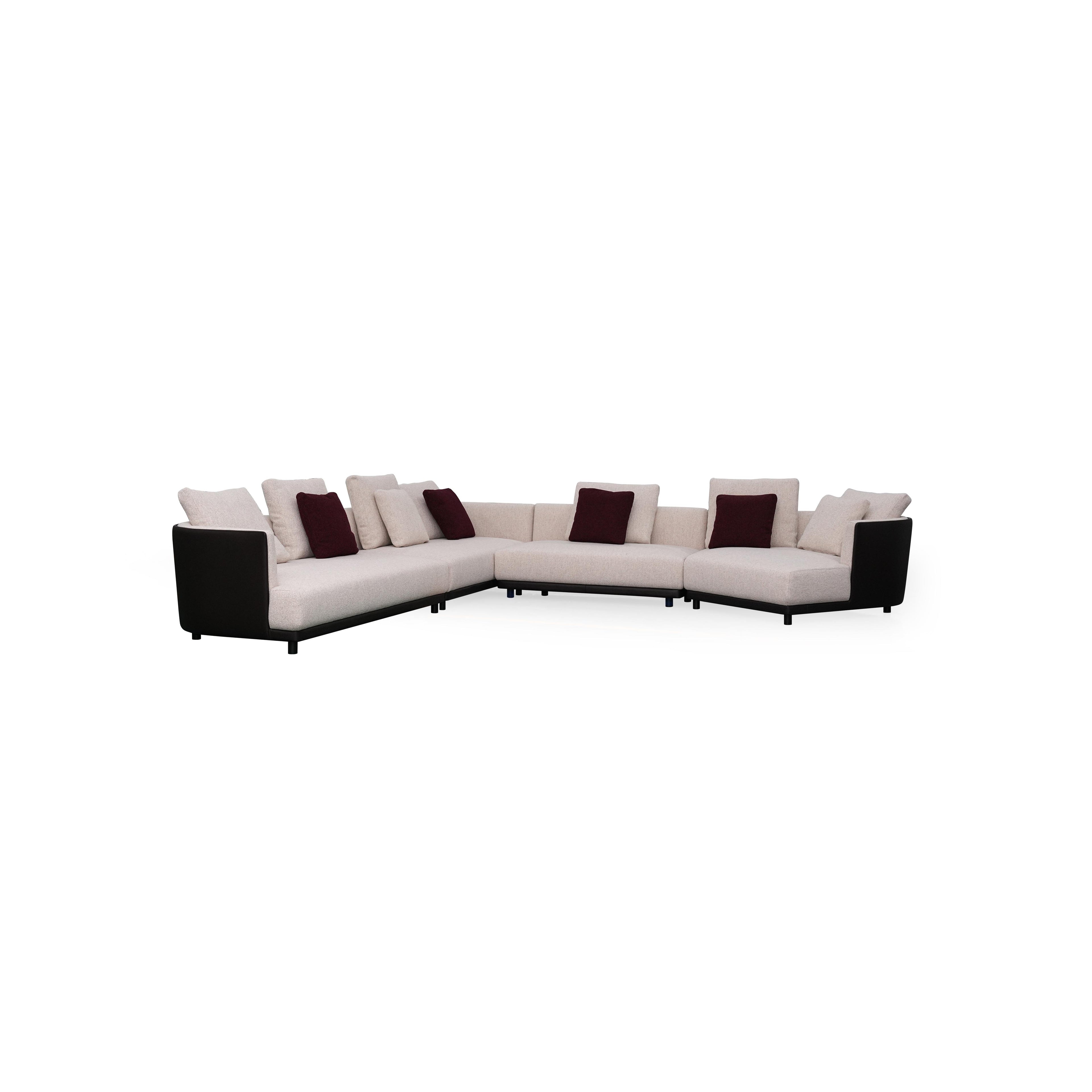 L-shaped sectional sofa with off-white fabric upholstery and dark gray armrests and base. Features multiple cushions, including two textured throw pillows. Supported by short, dark legs. Designed for seating and lounging. Category: furniture/sofas