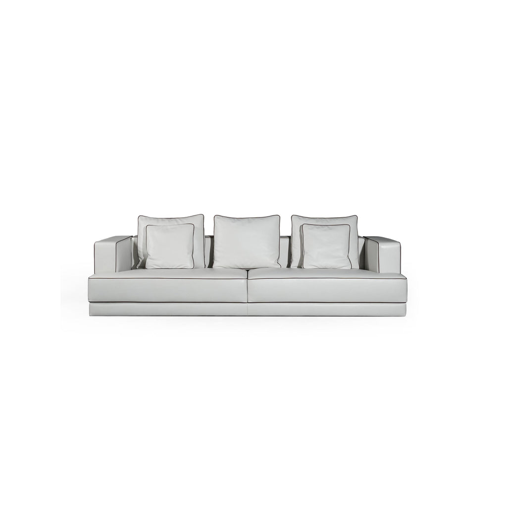 A three-seater sofa with light gray upholstery and matching square cushions, featuring defined armrests, a low-profile base, and subtle stitching along seams. Designed for seating, it has a modern, minimalist silhouette with no visible legs or hardware. Category: furniture/southern-style-sofas