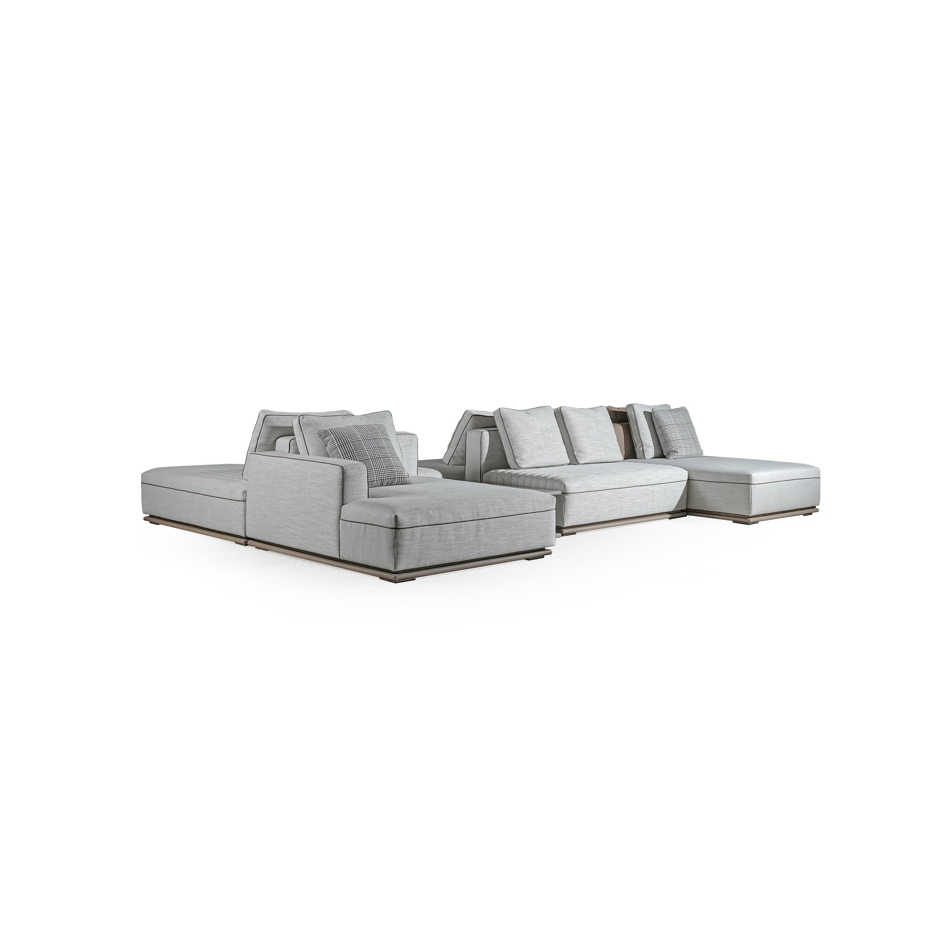 Modular sectional sofa with light gray fabric upholstery, featuring multiple cushions, defined armrests, and low-profile wooden base. Includes patterned throw pillows. Designed for lounging and seating arrangements. Category: furniture/sofas