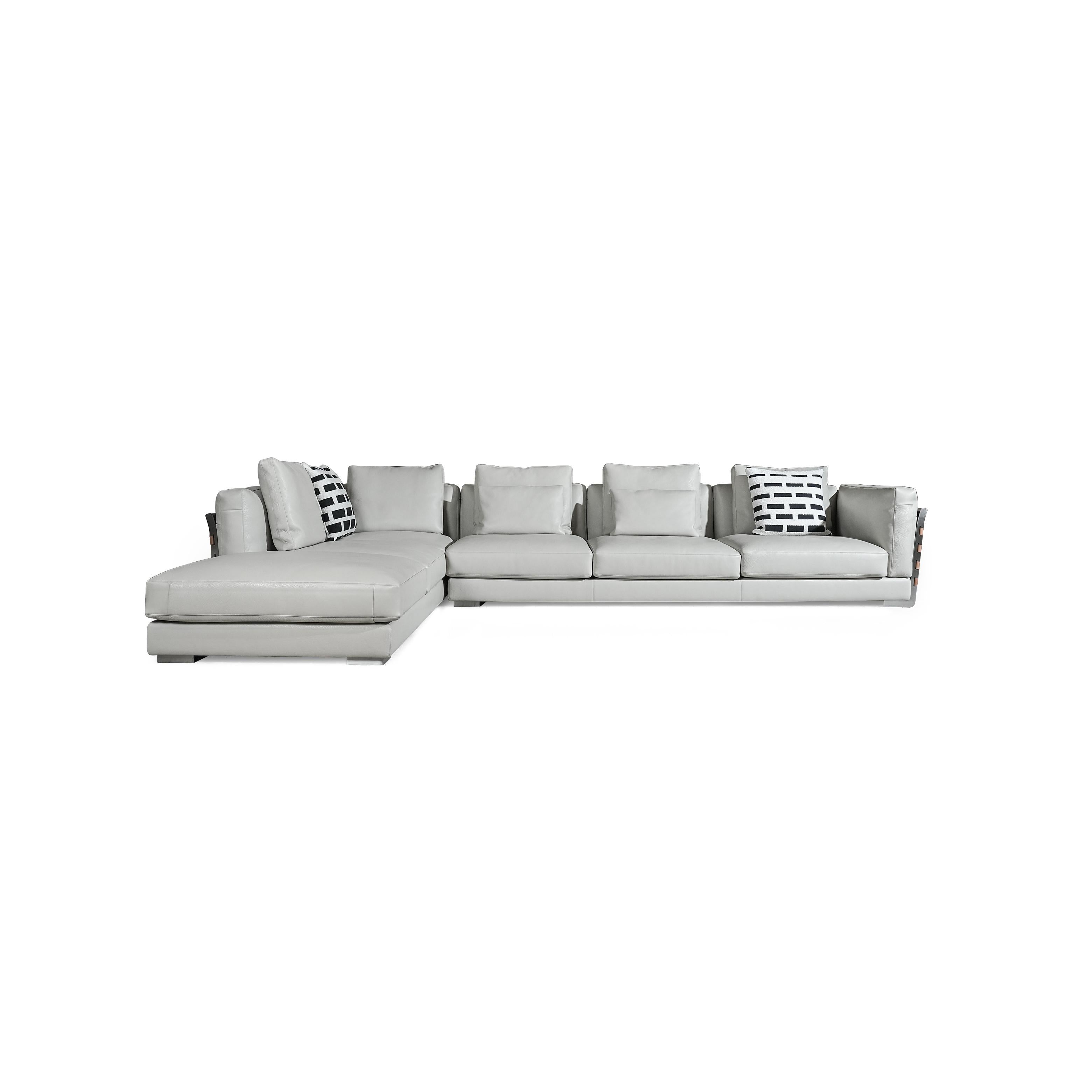 This is a sectional sofa with light gray upholstery and a brown woven panel on the left armrest. It has multiple cushions, including two black-and-white patterned pillows. The sofa has low-profile legs and a continuous backrest. It is designed for seating and lounging. Category: furniture/sofas