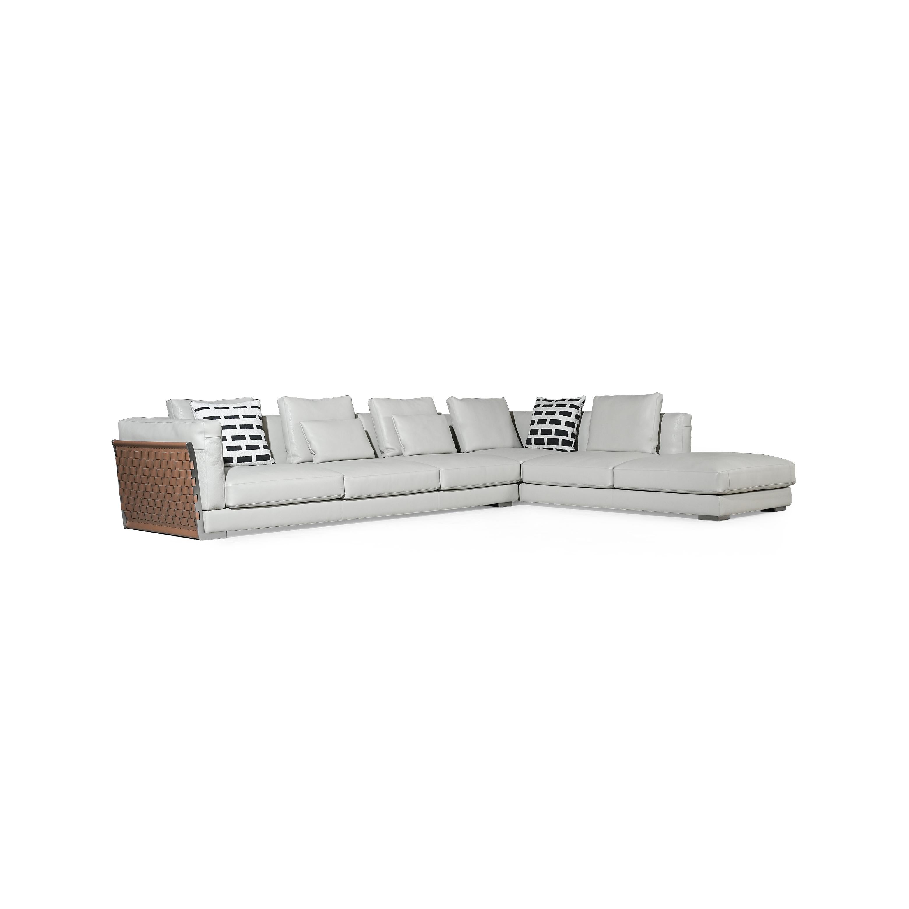 This is a sectional sofa with light gray upholstery and a brown woven panel on the left armrest. It has multiple cushions, including two black-and-white patterned pillows. The sofa has low-profile legs and a continuous backrest. It is designed for seating and lounging. Category: furniture/sofas