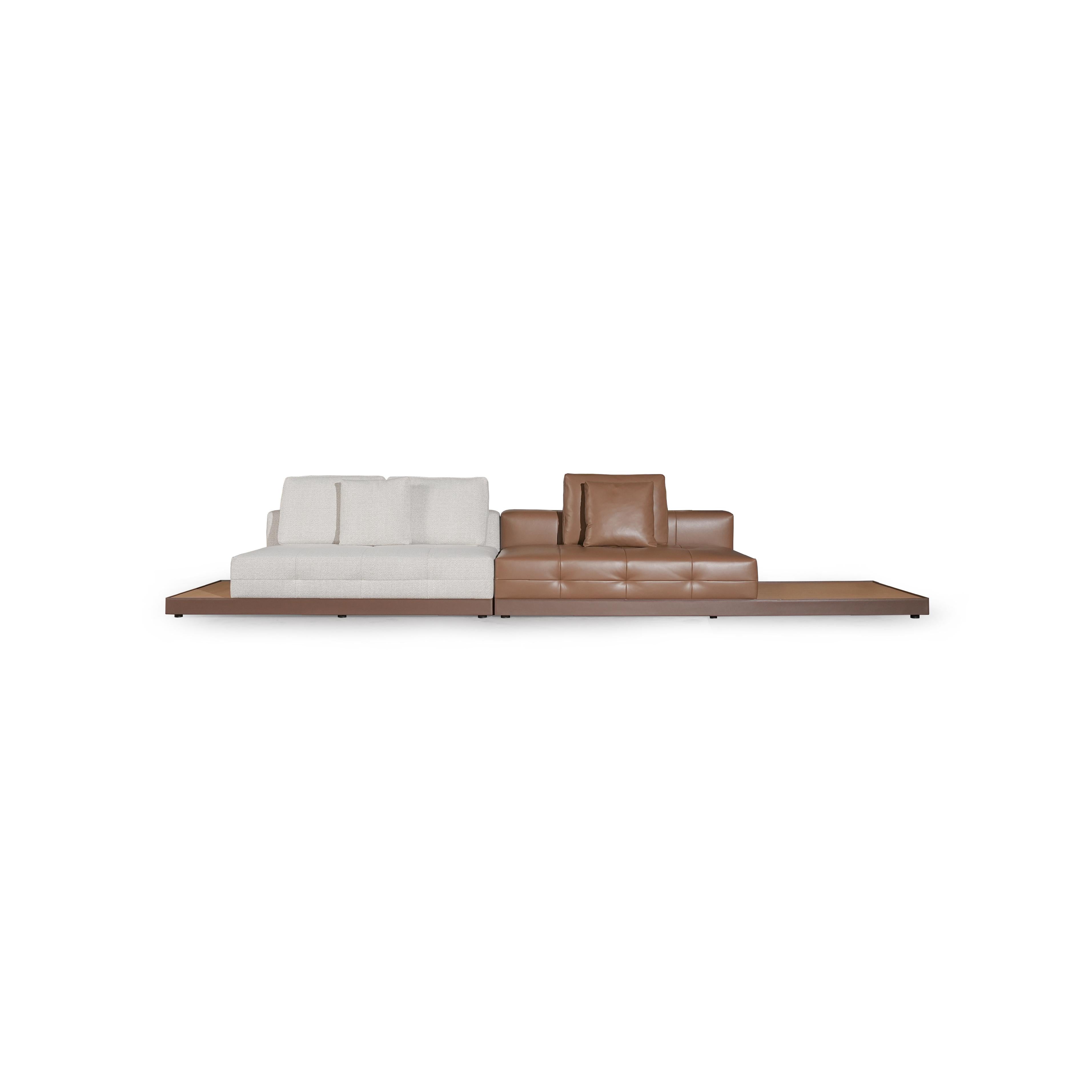 Modern sectional sofa with two-tone upholstery: left side in light textured fabric, right side in tan leather-like material. Features segmented backrests, square cushioned arms, low-profile metal legs, and distinct stitching. Designed for seating and lounging. Category: furniture/sofas