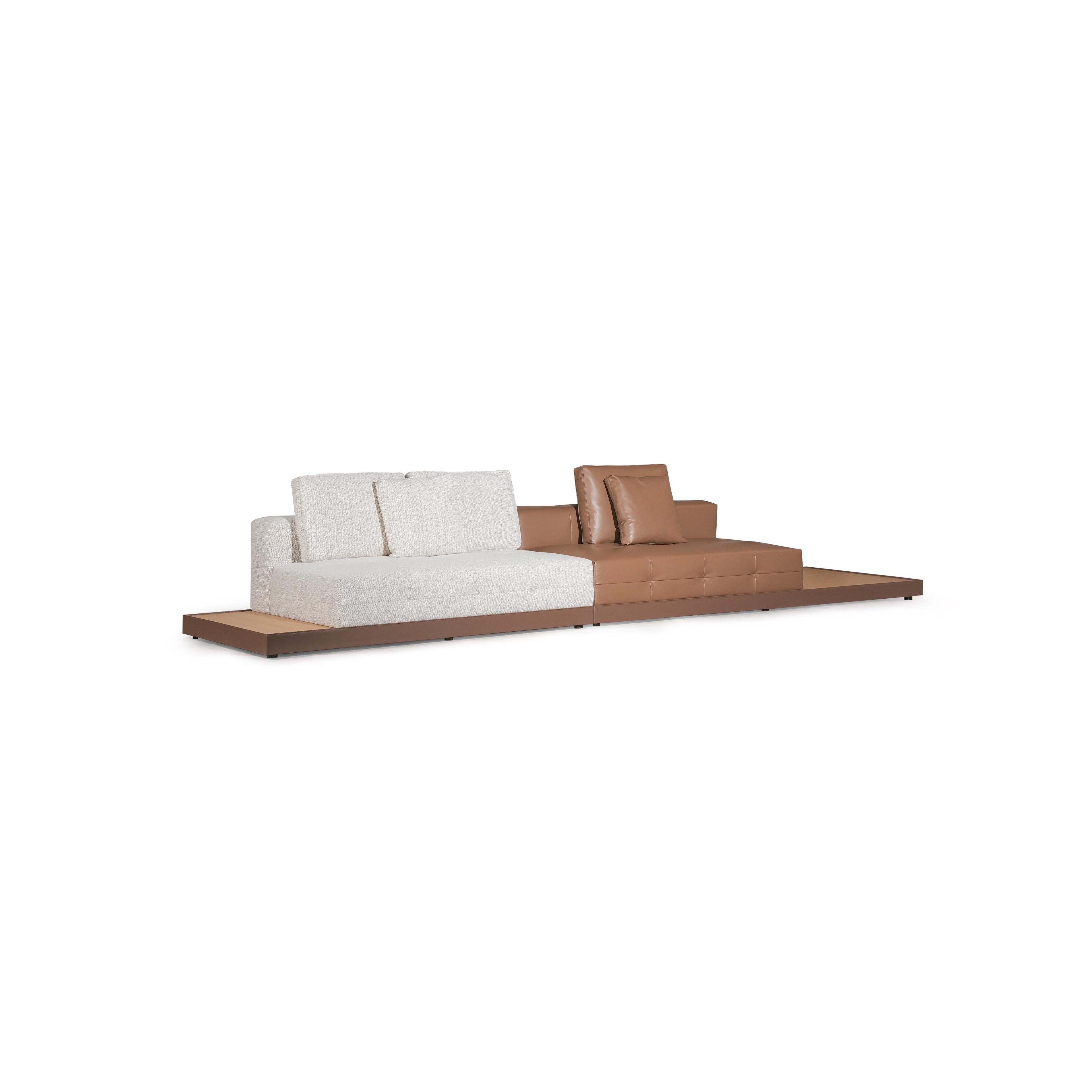 Modern sectional sofa with two-tone upholstery: left side in light textured fabric, right side in tan leather-like material. Features segmented backrests, square cushioned arms, low-profile metal legs, and distinct stitching. Designed for seating and lounging. Category: furniture/sofas