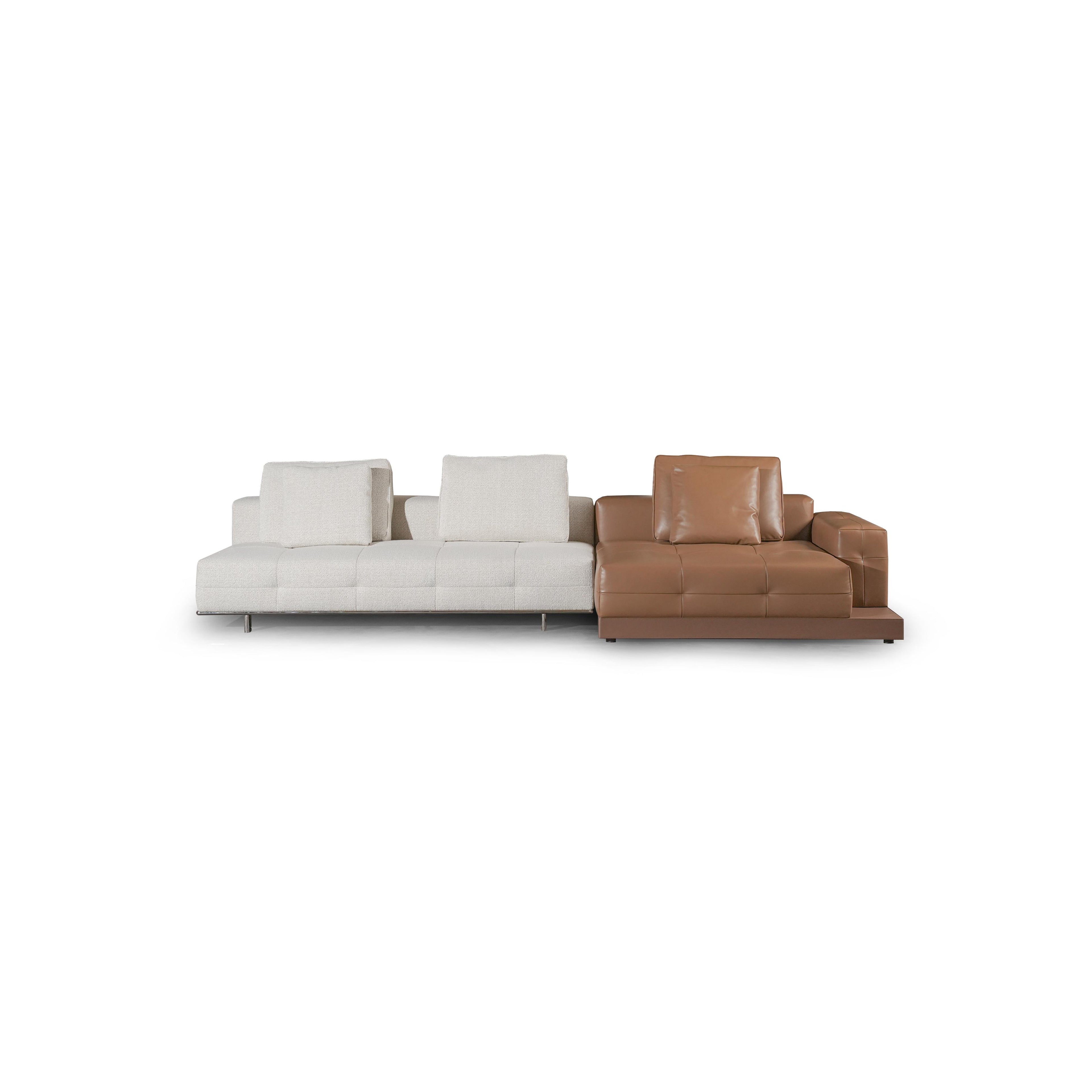 Modern sectional sofa with two-tone upholstery: left side in light textured fabric, right side in tan leather-like material. Features segmented backrests, square cushioned arms, low-profile metal legs, and distinct stitching. Designed for seating and lounging. Category: furniture/sofas