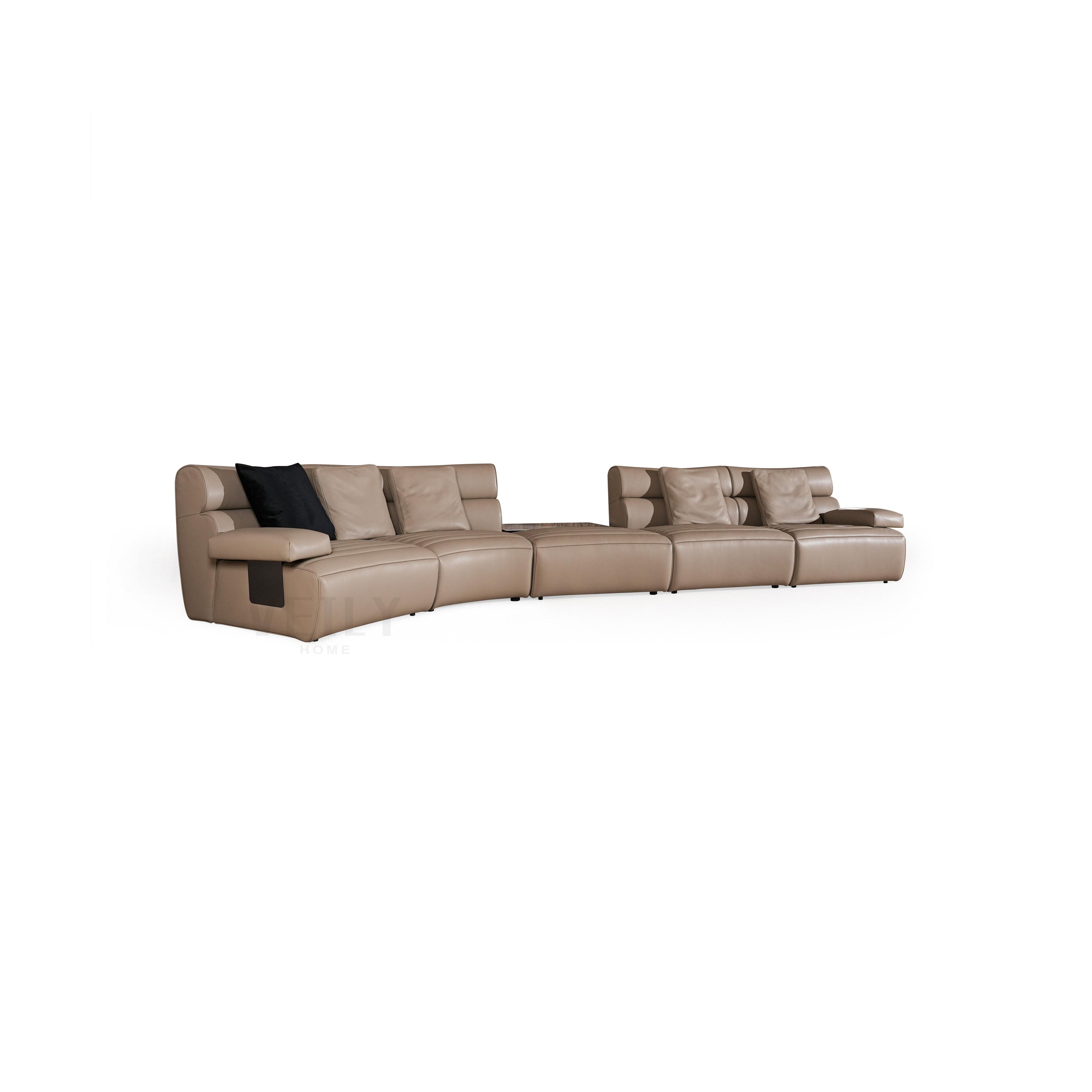 Modern sectional sofa with tan upholstery and one black cushion, featuring curved seating, segmented backrests, armrests, and low-profile legs; designed for lounging, with visible stitching and smooth surface texture. Category: furniture/sofas