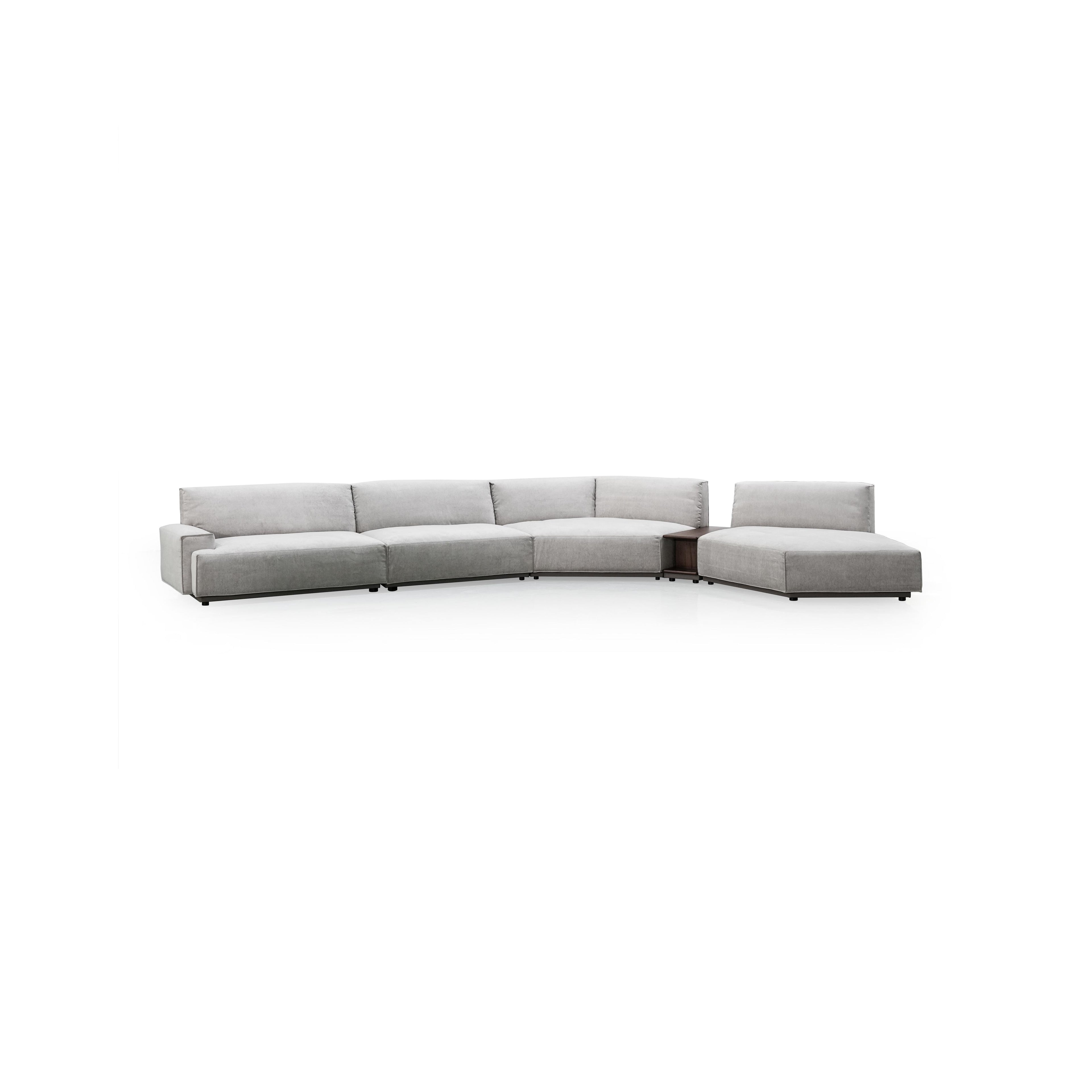 This is a sectional sofa with a light gray fabric upholstery, featuring a curved L-shape with multiple cushioned sections, low-profile black legs, and integrated armrests and backrests. It includes a built-in side table with a visible open compartment. Intended for seating and casual lounging. Category: furniture/sofas