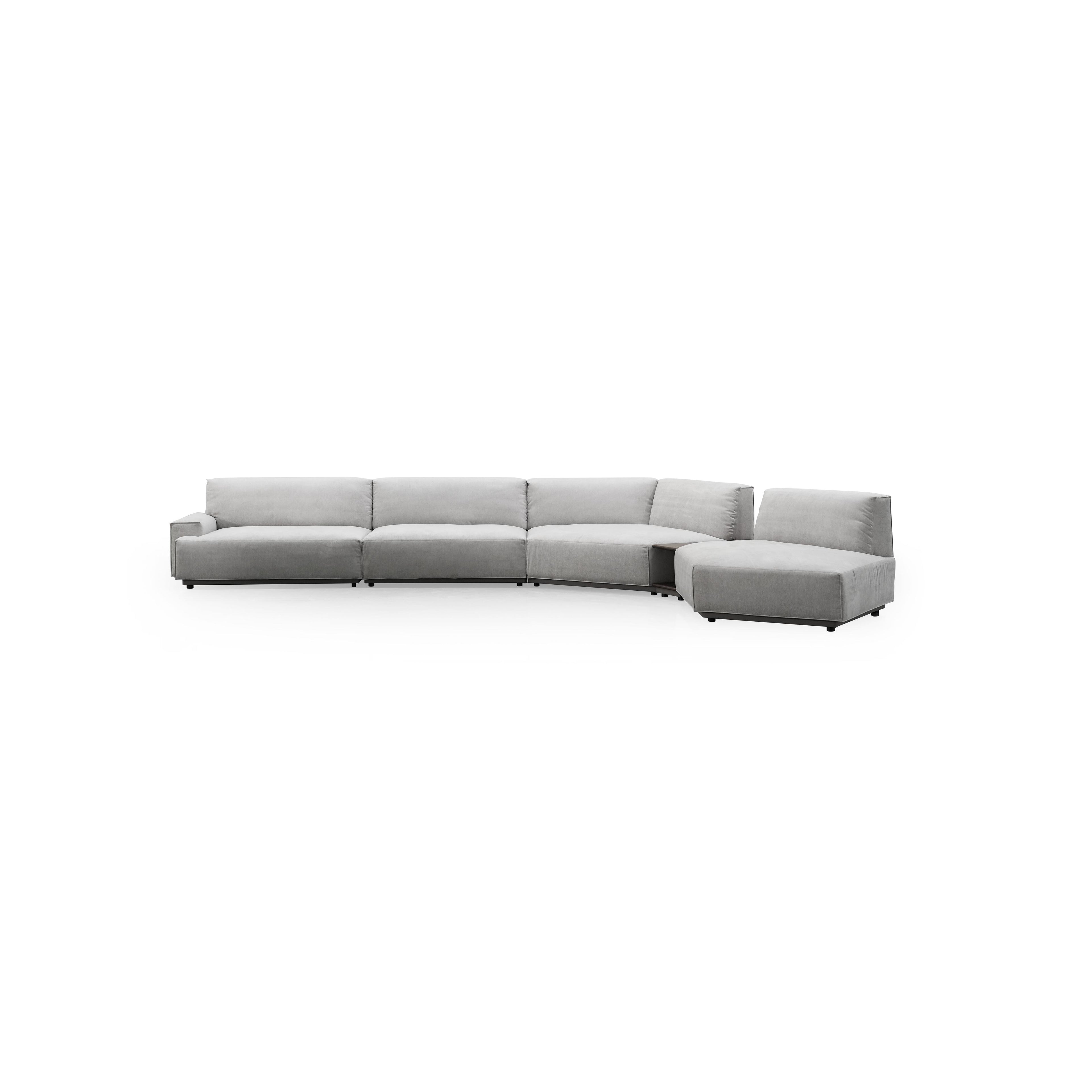 This is a sectional sofa with a light gray fabric upholstery, featuring a curved L-shape with multiple cushioned sections, low-profile black legs, and integrated armrests and backrests. It includes a built-in side table with a visible open compartment. Intended for seating and casual lounging. Category: furniture/sofas