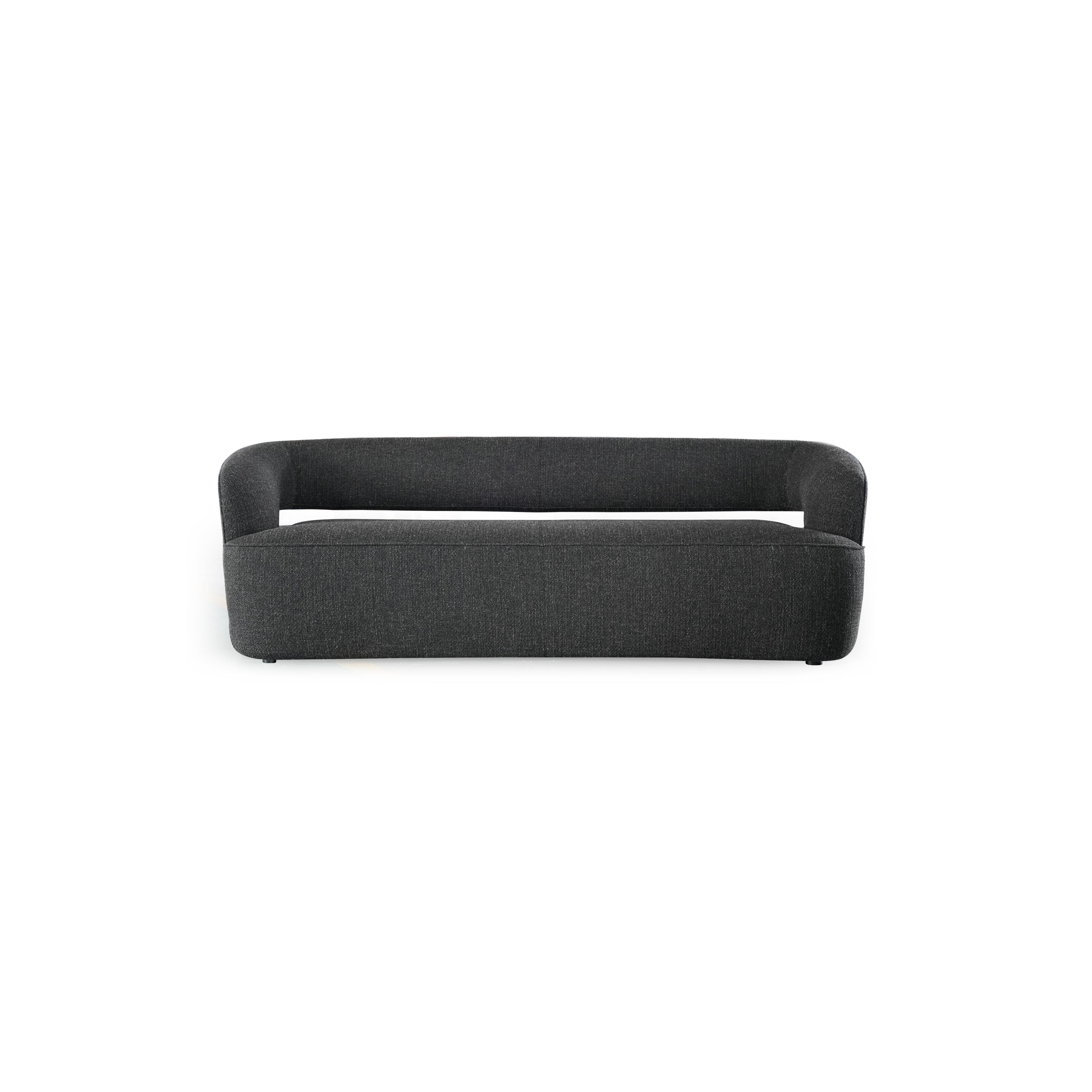 Dark gray upholstered sofa with rounded arms and low backrest, featuring a single cushioned seat and two small feet. Fabric has a textured weave. Designed for seating. Category: furniture/sofas