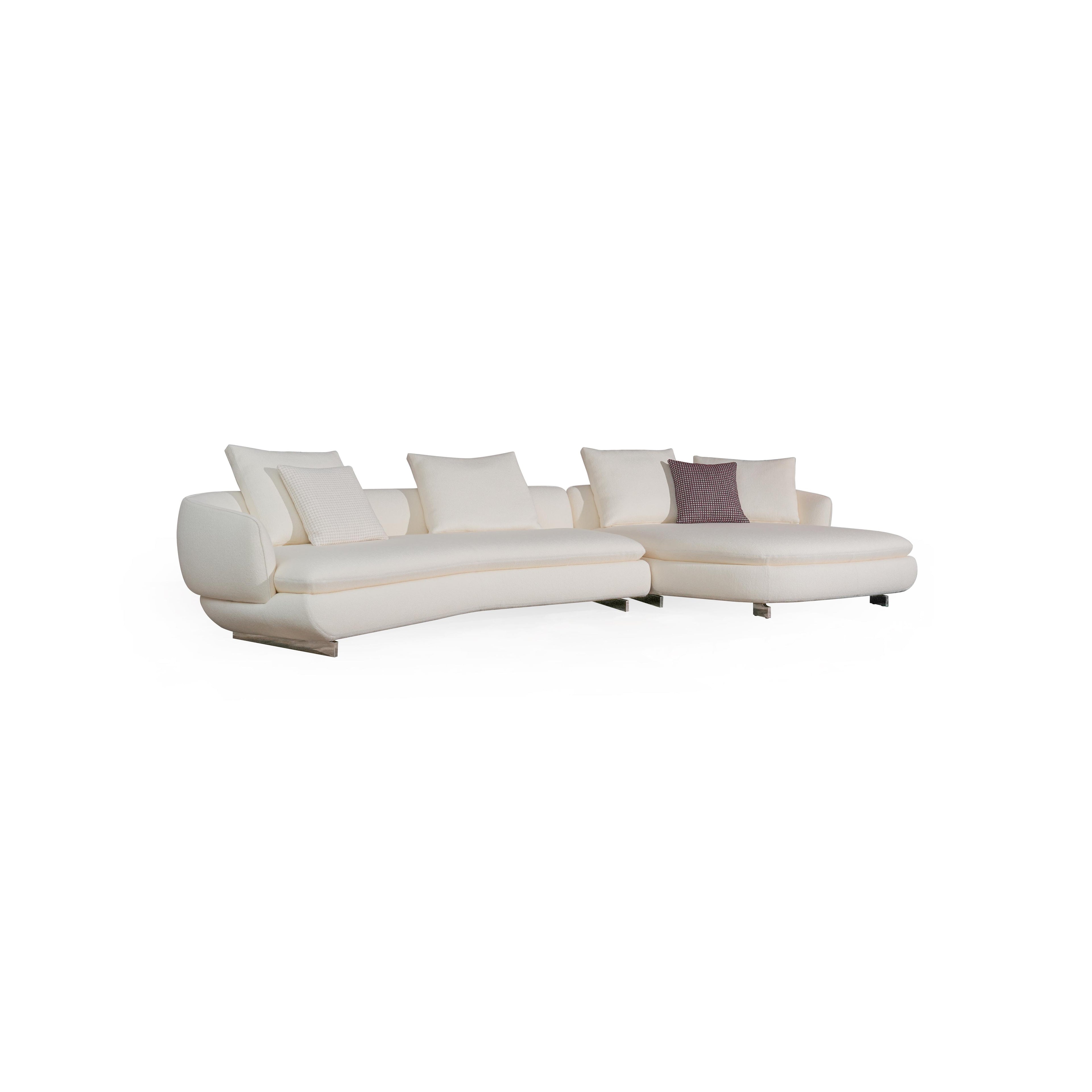 Modern sectional sofa with off-white fabric upholstery, curved backrest, padded armrests, and low-profile metal legs. Features multiple cushions, including one with a textured pattern. Designed for seating and lounging. Category: furniture/sofas