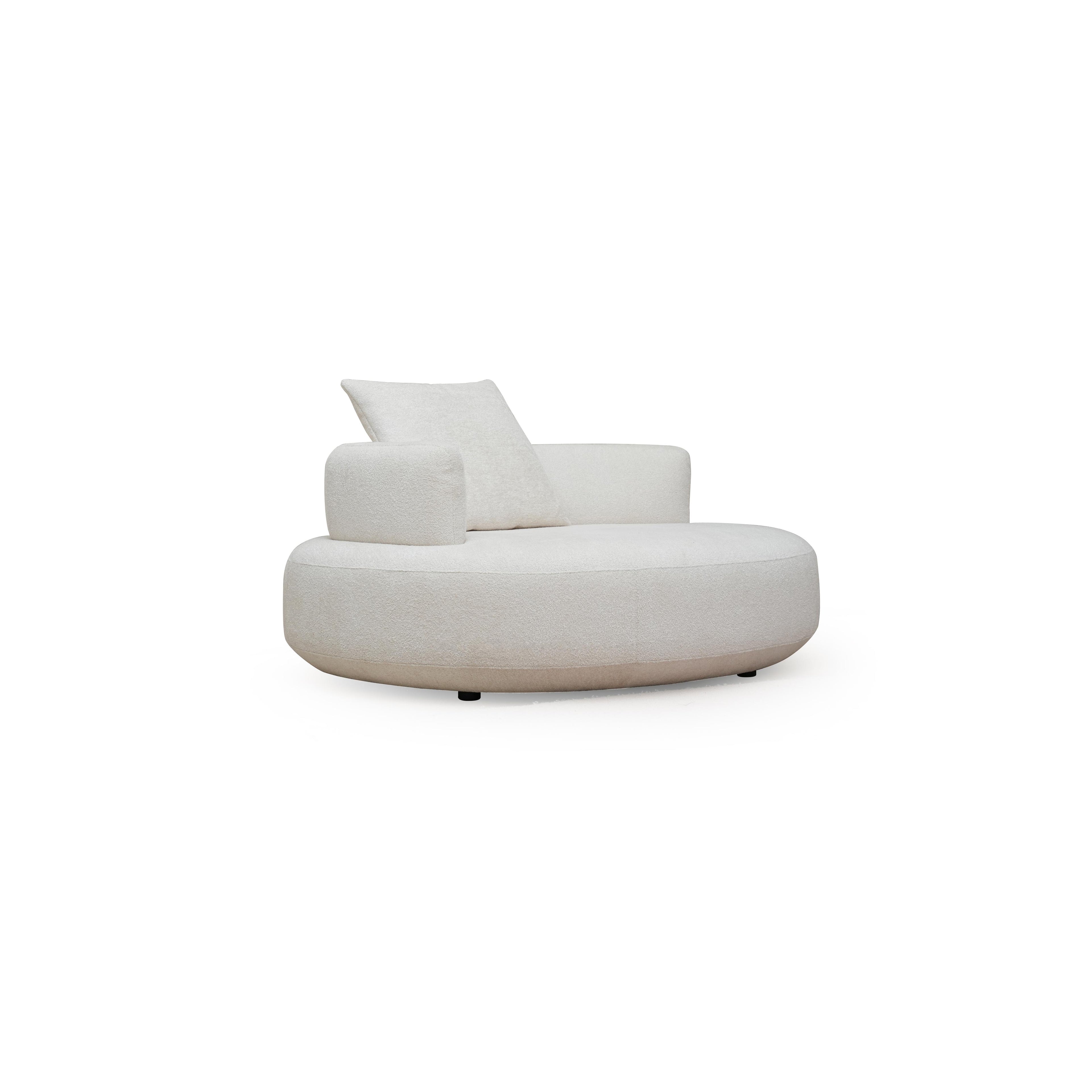 This is a round lounge chair with a single cushioned backrest and one armrest, upholstered in a light beige textured fabric. It rests on four small black legs. Designed for seated relaxation, it features a continuous curved seat and a matching pillow. Category: Furniture > Sofas & Chairs > Lounge Chairs