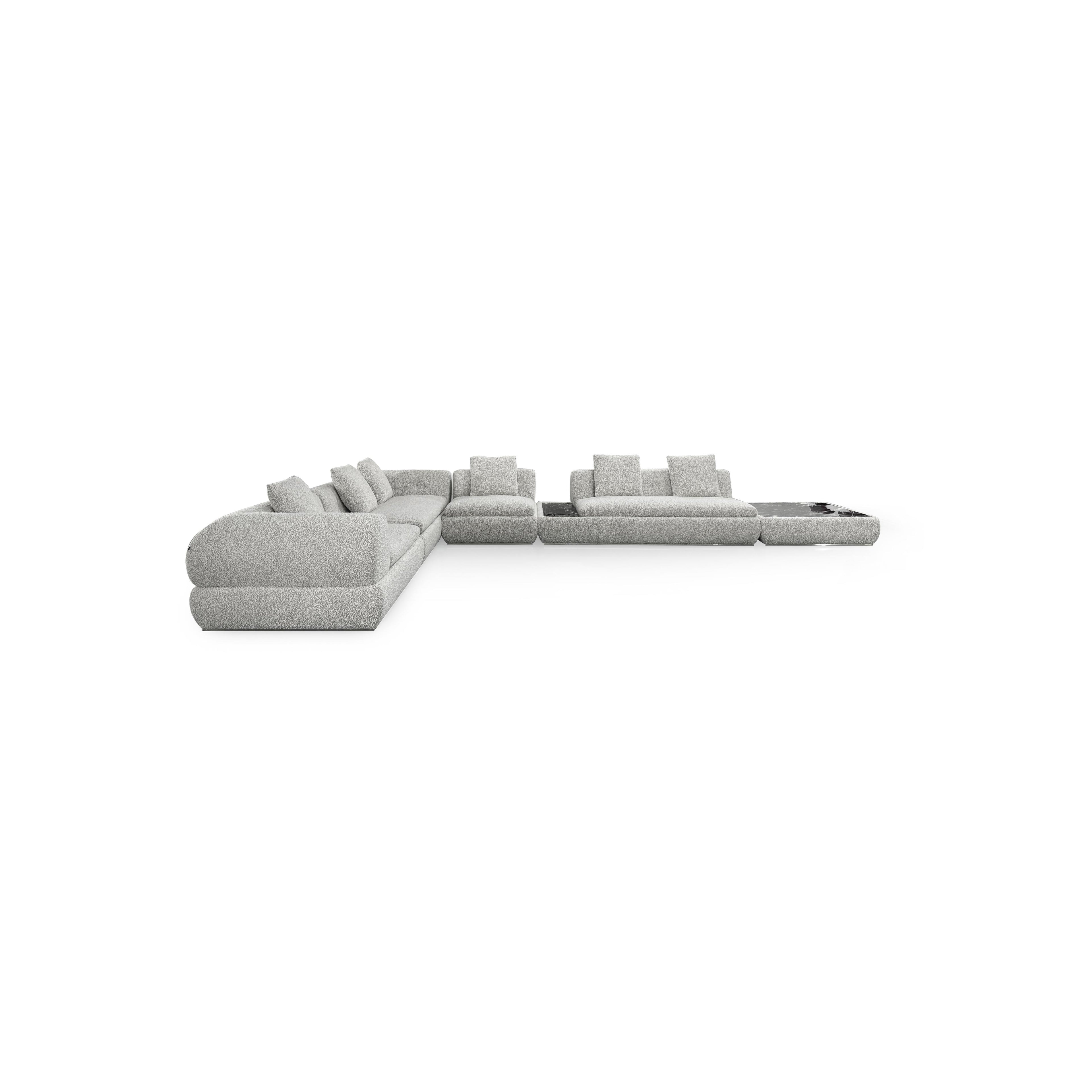 Modular sectional sofa with light gray fabric upholstery, featuring multiple cushioned seating sections, low-profile arms, and a central coffee table with a dark surface. Designed for lounging, it includes visible seam lines and soft, rounded contours. Category: furniture/sofas