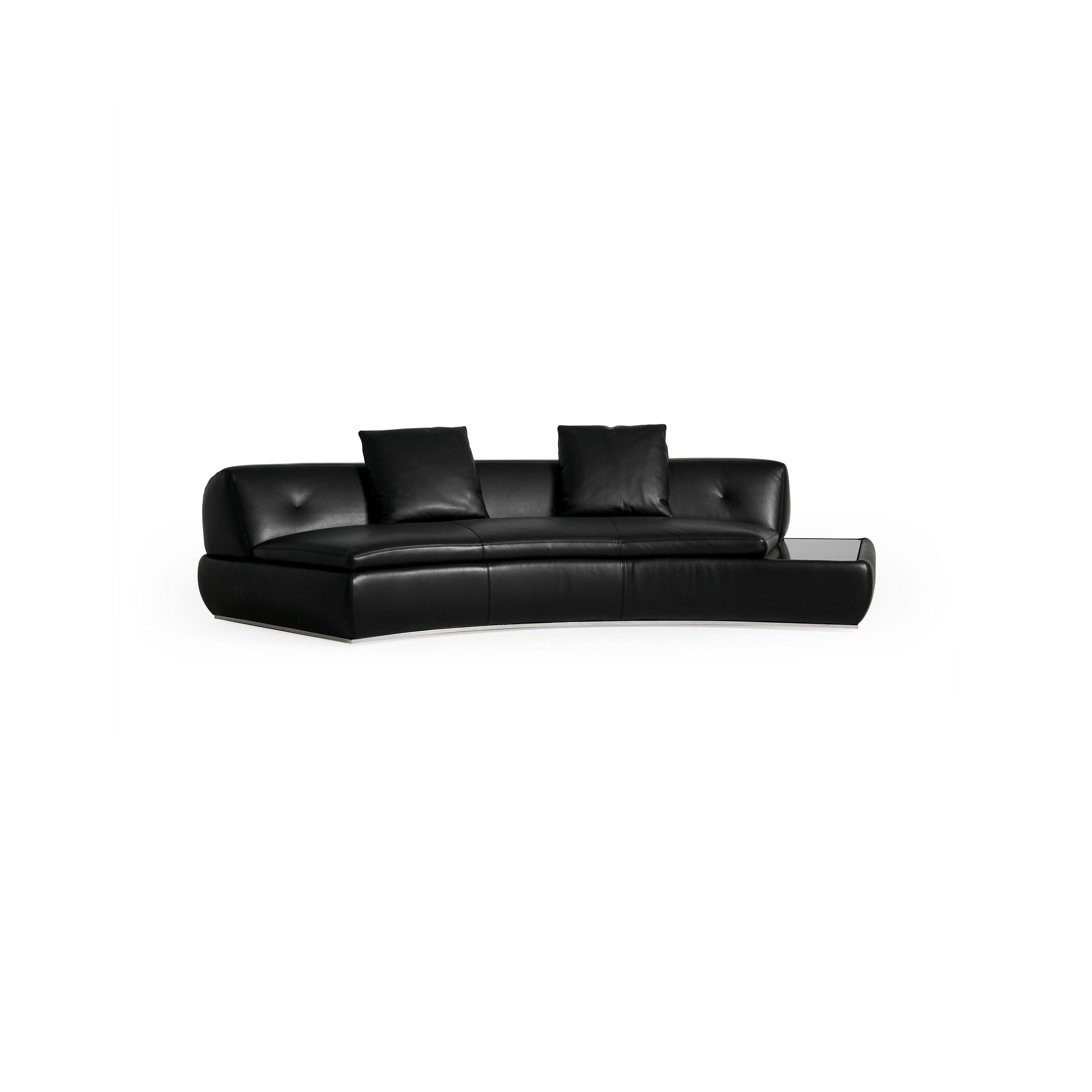 Modular sectional sofa with light gray fabric upholstery, featuring multiple cushioned seating sections, low-profile arms, and a central coffee table with a dark surface. Designed for lounging, it includes visible seam lines and soft, rounded contours. Category: furniture/sofas
