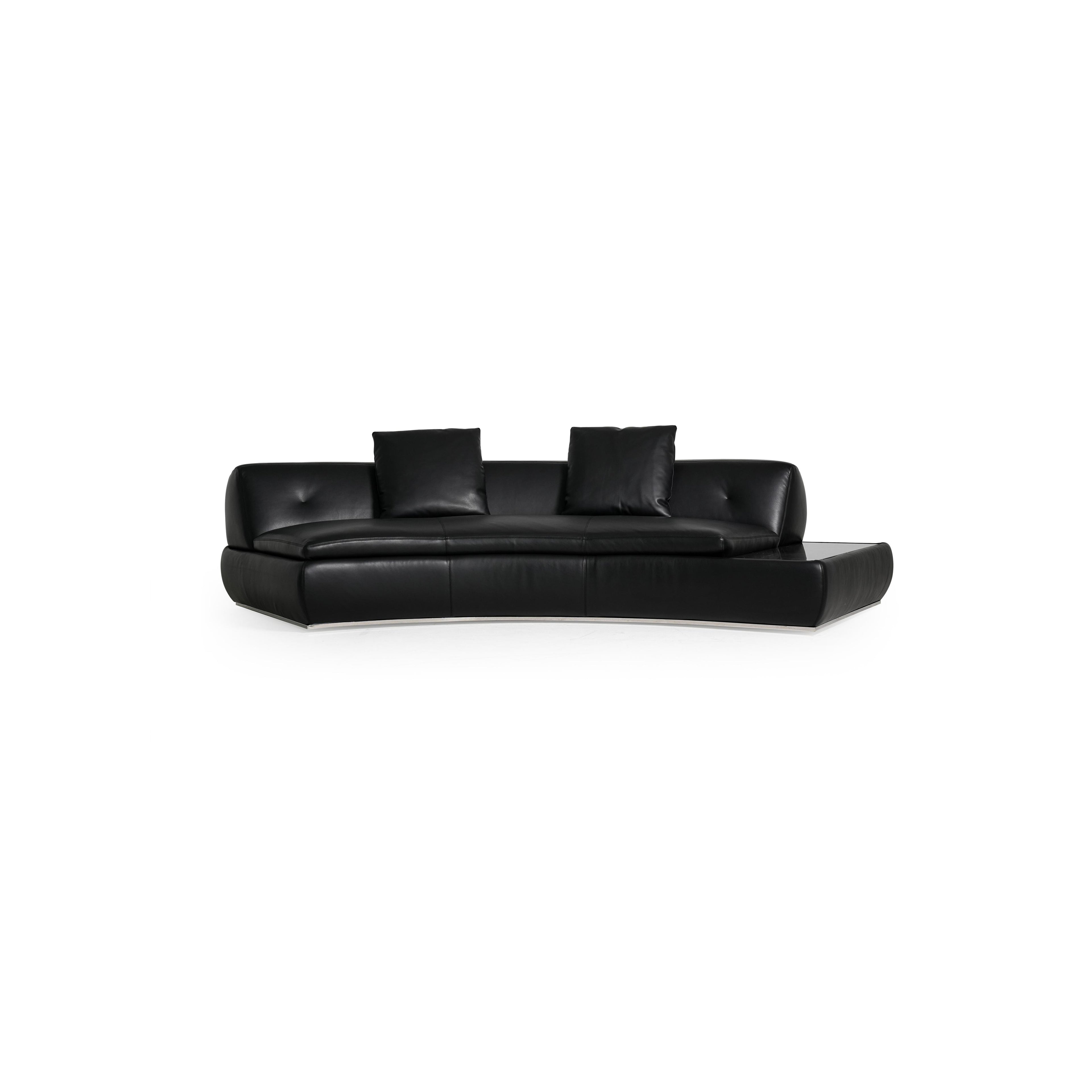 Modular sectional sofa with light gray fabric upholstery, featuring multiple cushioned seating sections, low-profile arms, and a central coffee table with a dark surface. Designed for lounging, it includes visible seam lines and soft, rounded contours. Category: furniture/sofas