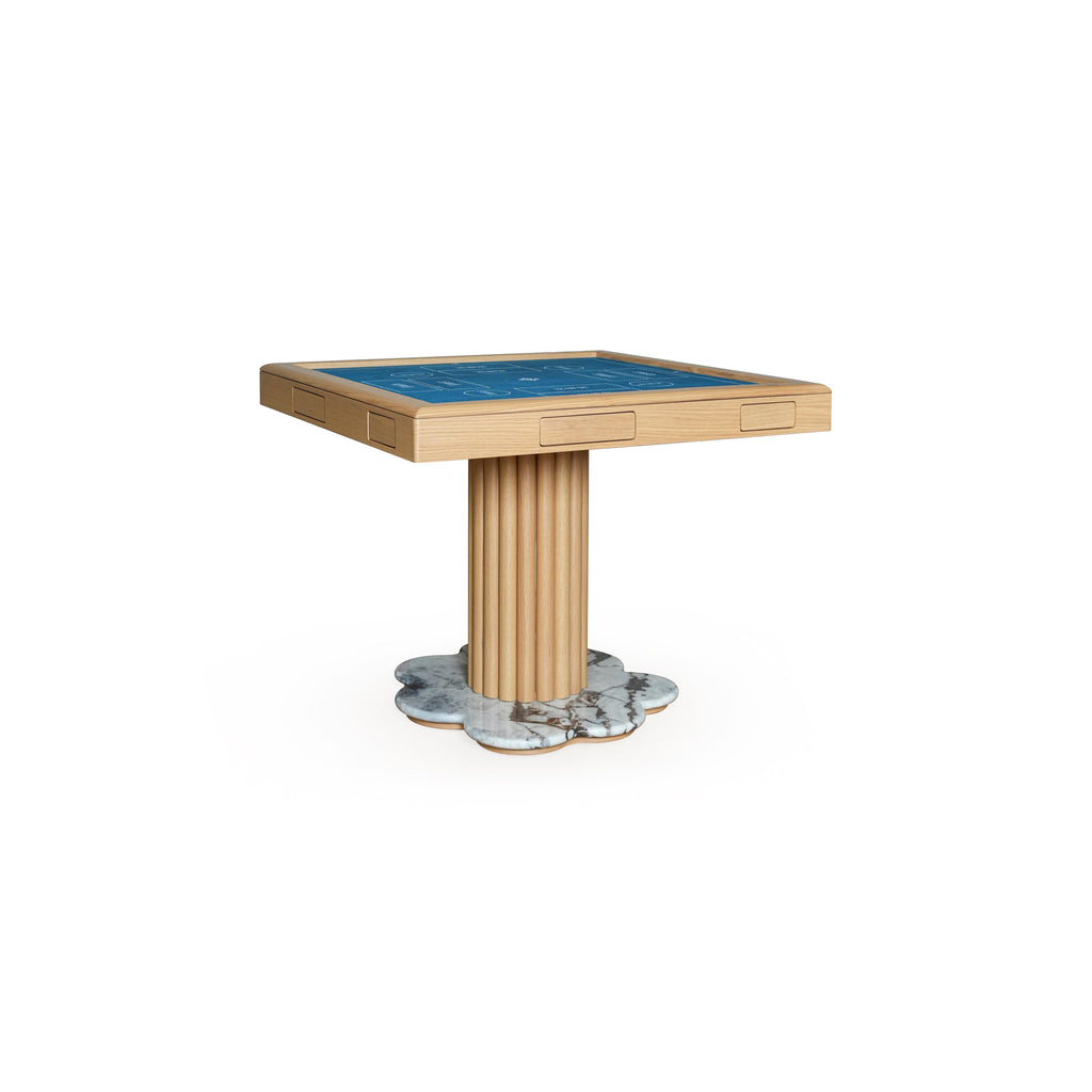 This is a rectangular gaming table with a blue playing surface, light wood frame, and fluted central pedestal leg resting on a marbled, petal-shaped base. It has two recessed rectangular drawers on the tabletop. Intended for card or board games, it features visible wood grain and marble texture. Category: furniture/tabletops
