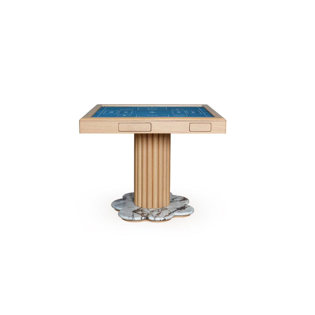 This is a rectangular gaming table with a blue playing surface, light wood frame, and fluted central pedestal leg resting on a marbled, petal-shaped base. It has two recessed rectangular drawers on the tabletop. Intended for card or board games, it features visible wood grain and marble texture. Category: furniture/tabletops
