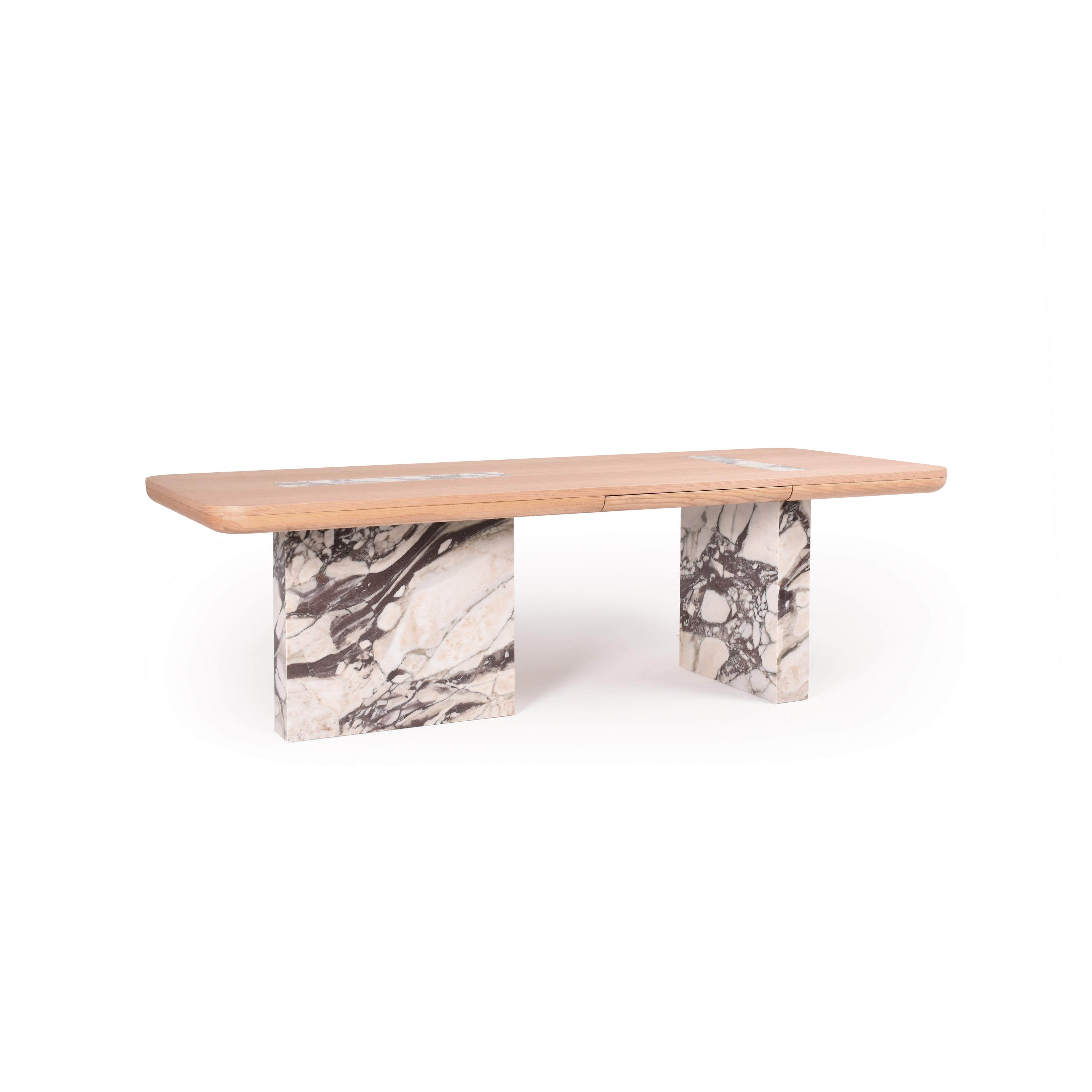 Rectangular dining table with light wood top and two thick marble legs featuring white and dark veining. Table has a central seam dividing the top. Intended for dining or workspace use. Category: furniture/dining-tables