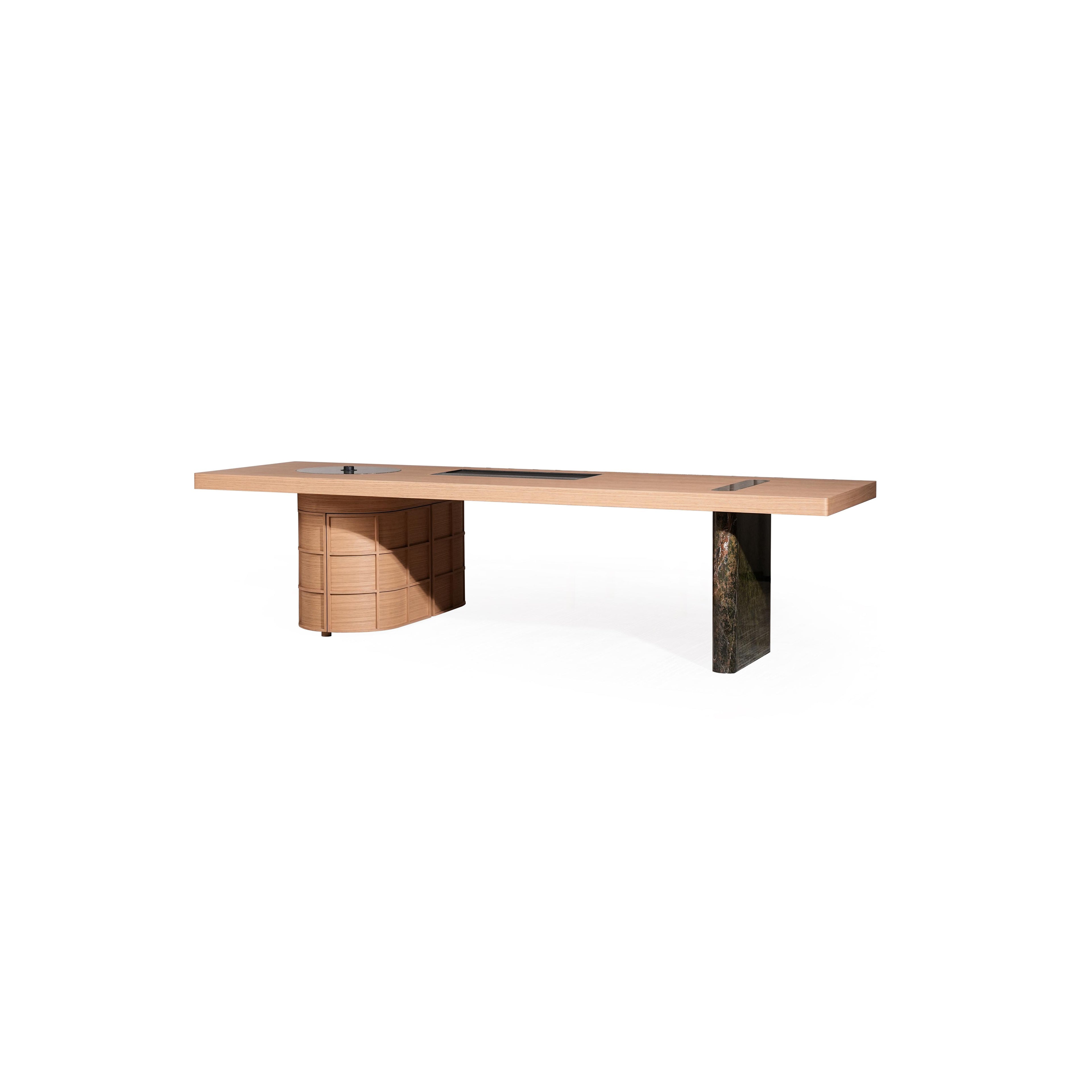 Long rectangular desk with light wood top and two distinct legs â€?one cylindrical with stacked drawers, the other solid dark stone-like material. Features three recessed cutouts on surface. Intended for work or study. Category: furniture/desks