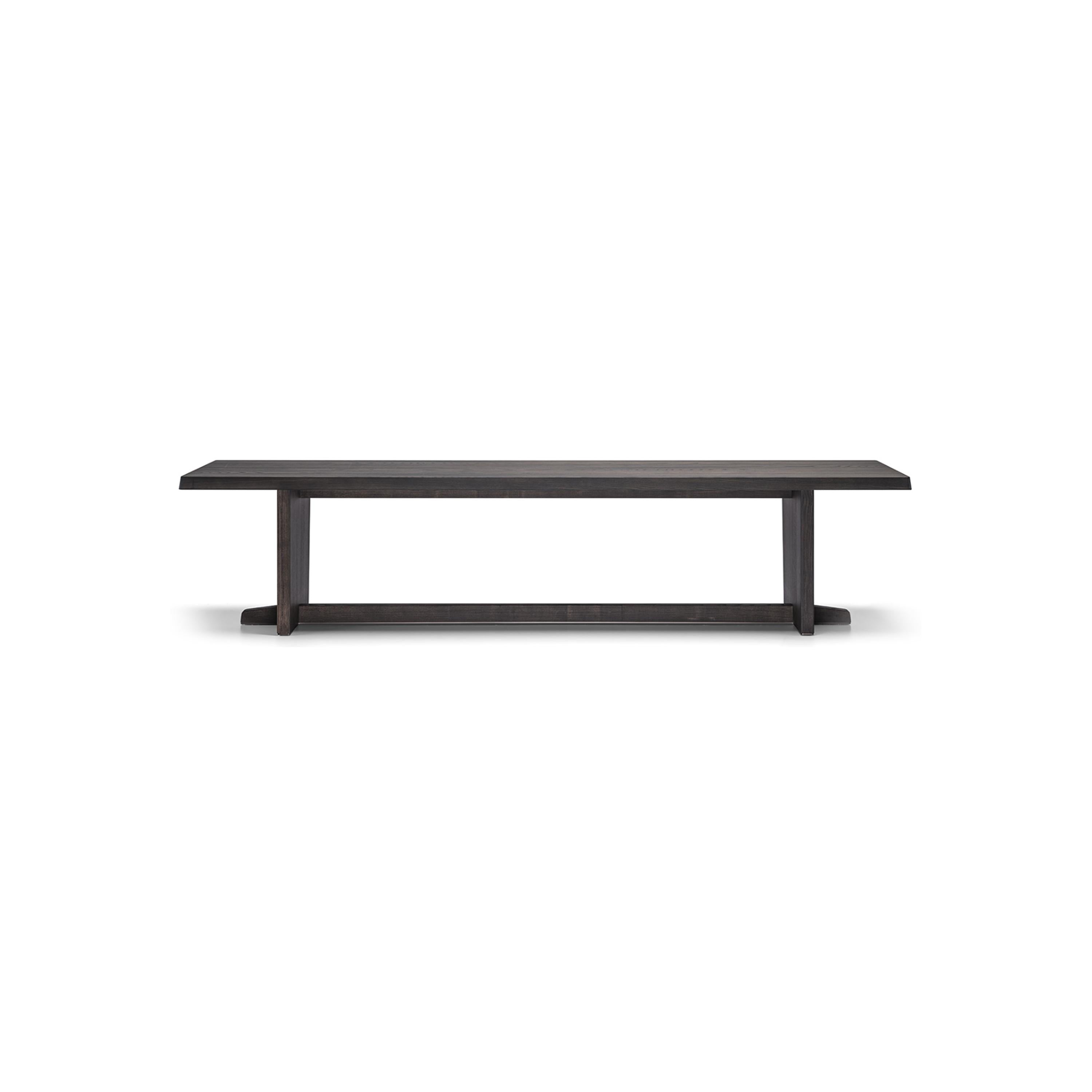 A long rectangular dining table with a dark wood finish and visible grain. It has two vertical legs connected by a horizontal stretcher bar. The tabletop is flat and smooth. Intended for dining, it features a minimalist design with no drawers or handles. Category: furniture/dining-tables